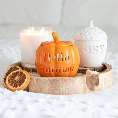 Acorn tealight holder on a wooden tray with candles and dried orange slices.