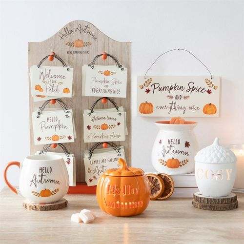 Acorn-shaped tealight holder with cozy autumn decor setting and themed signs.