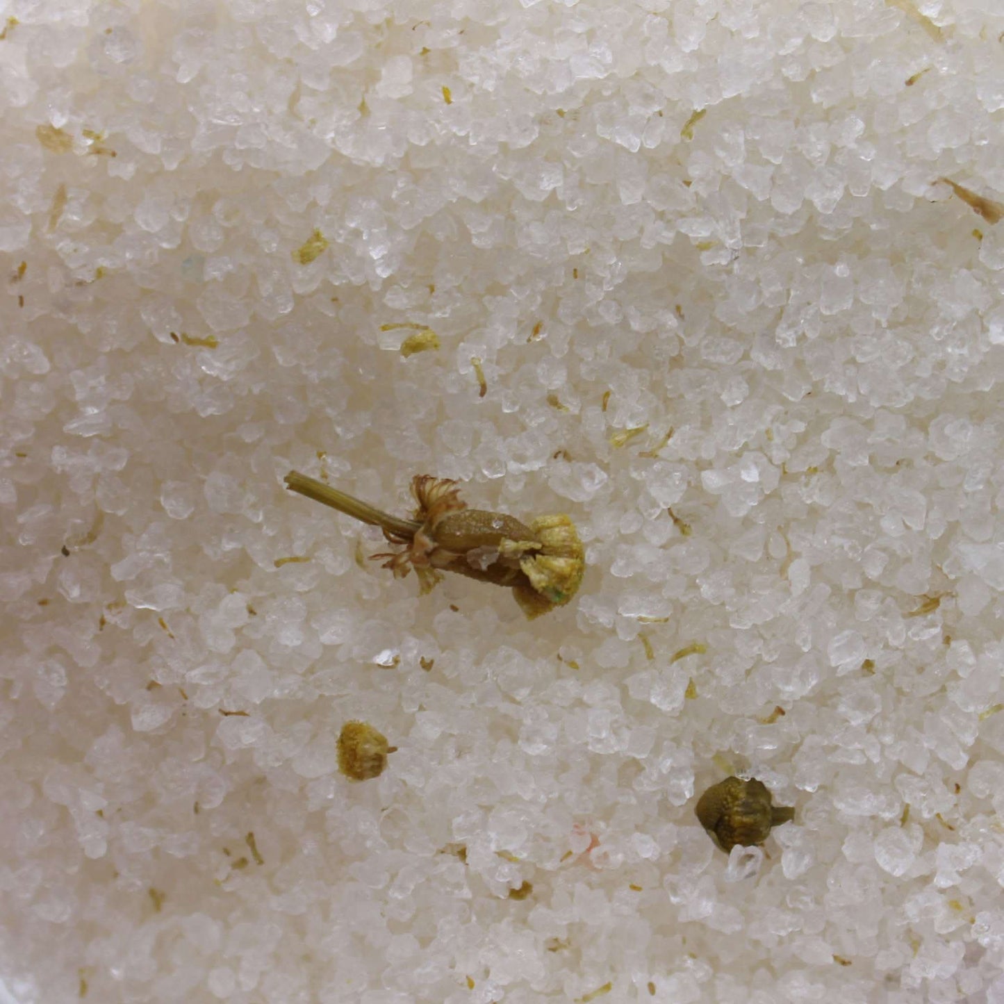 Close-up of mineral-rich Himalayan bath salt crystals with chamomile flowers