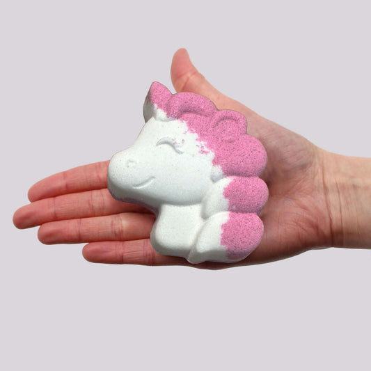 Hand holding pink and white unicorn shaped bathbomb scented with passion fruit, 100g Unicorn Bathbomb