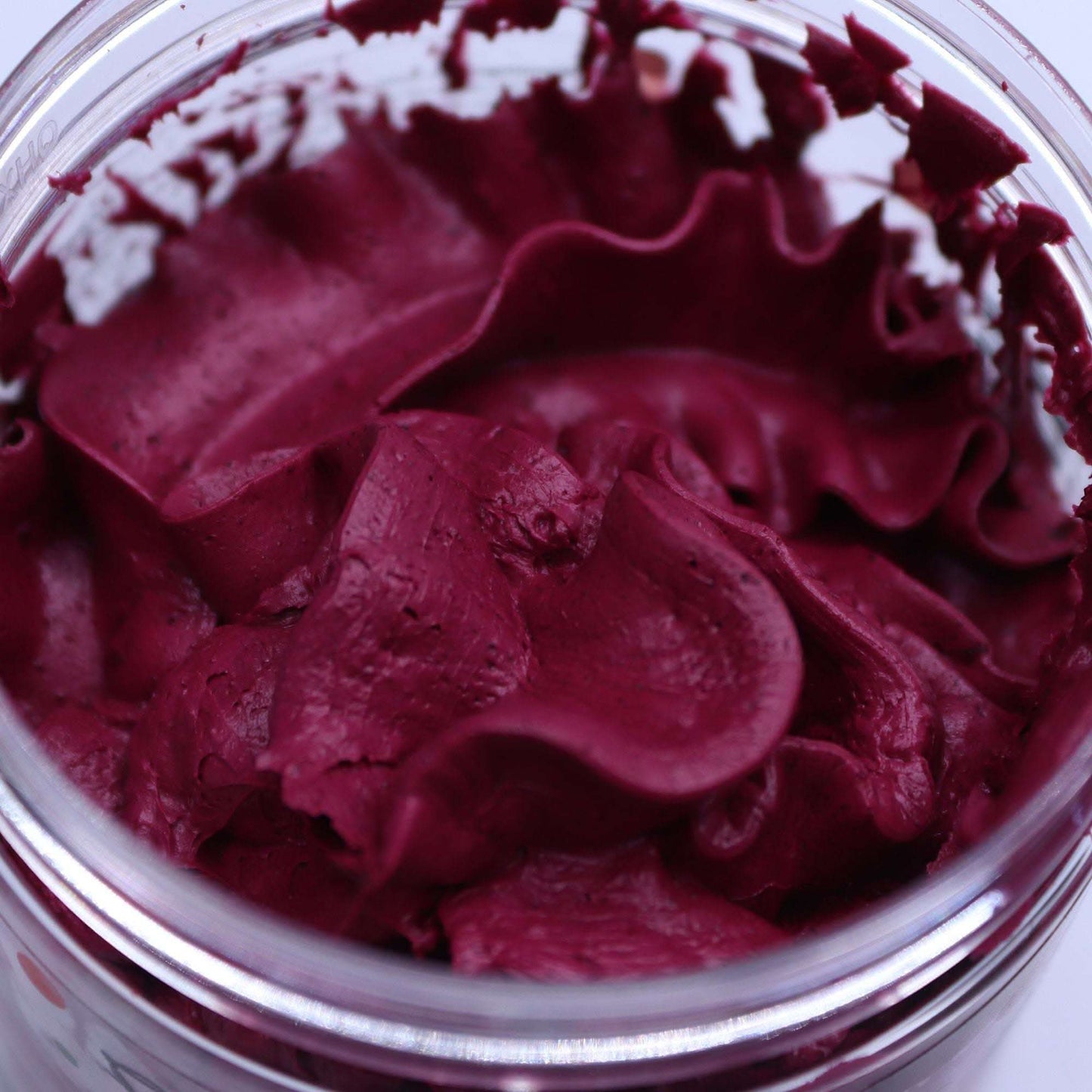 close-up of deep purple fruity whipped soap with creamy texture in a jar