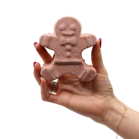 Hand holding a textured brown gingerbread man shaped bath bomb from the Christmas Fun Bath Bomb Gift Pack