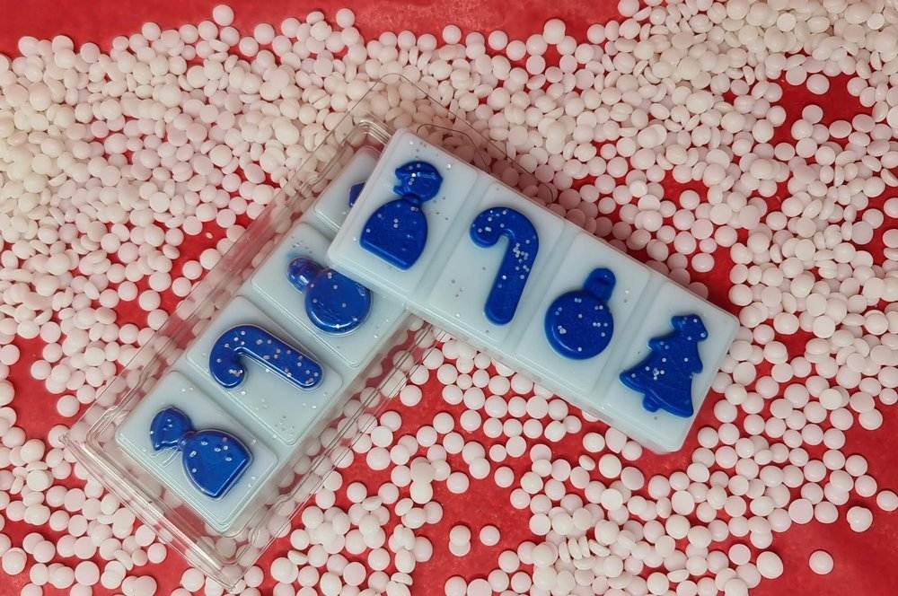 Festive Snuggles wax melt snap bars with winter-themed designs on a textured background.