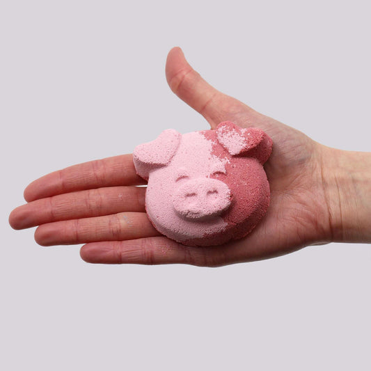 Pig Bath bomb shaped like a pig's face in two shades of pink with textured surface held in a hand