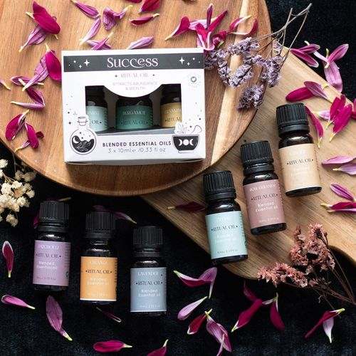Set of 3 Love Ritual Blended Essential Oils with Thyme, Rose Geranium, and Ginger on a wooden tray surrounded by petals.