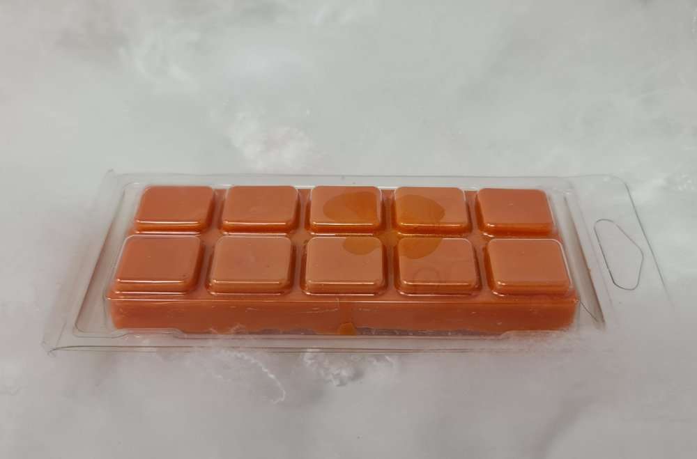 Orange pumpkin clamshell wax melt with 10 segments, infused with cinnamon, nutmeg, clove, and ginger scents.