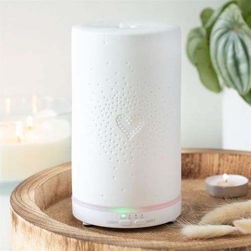 White Ceramic Heart Scatter Electric Aroma Diffuser on wooden tray with lit candle and decor.