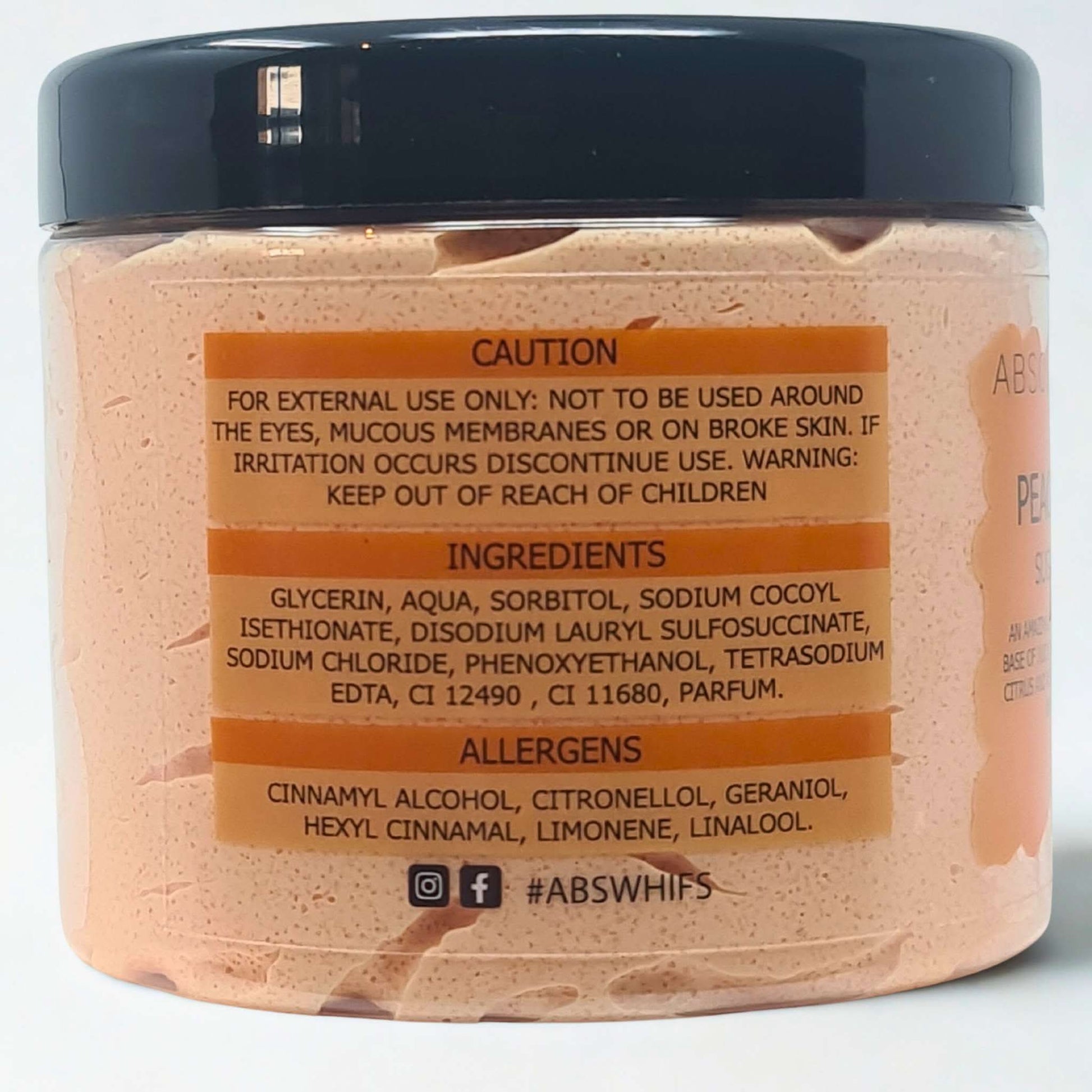 Pomegranate Noir Sugar Body Scrub jar with ingredient and caution labels on pink exfoliating scrub background