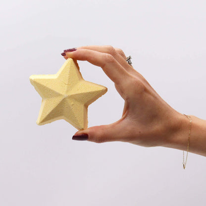 Hand holding Follow the Star star-shaped Christmas bath bomb with cozy winter scent