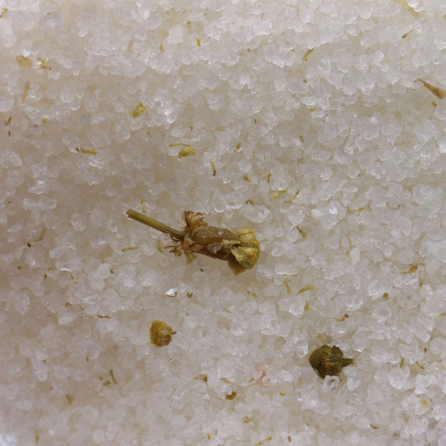 Close-up of mineral-rich Himalayan bath salt crystals with chamomile flowers