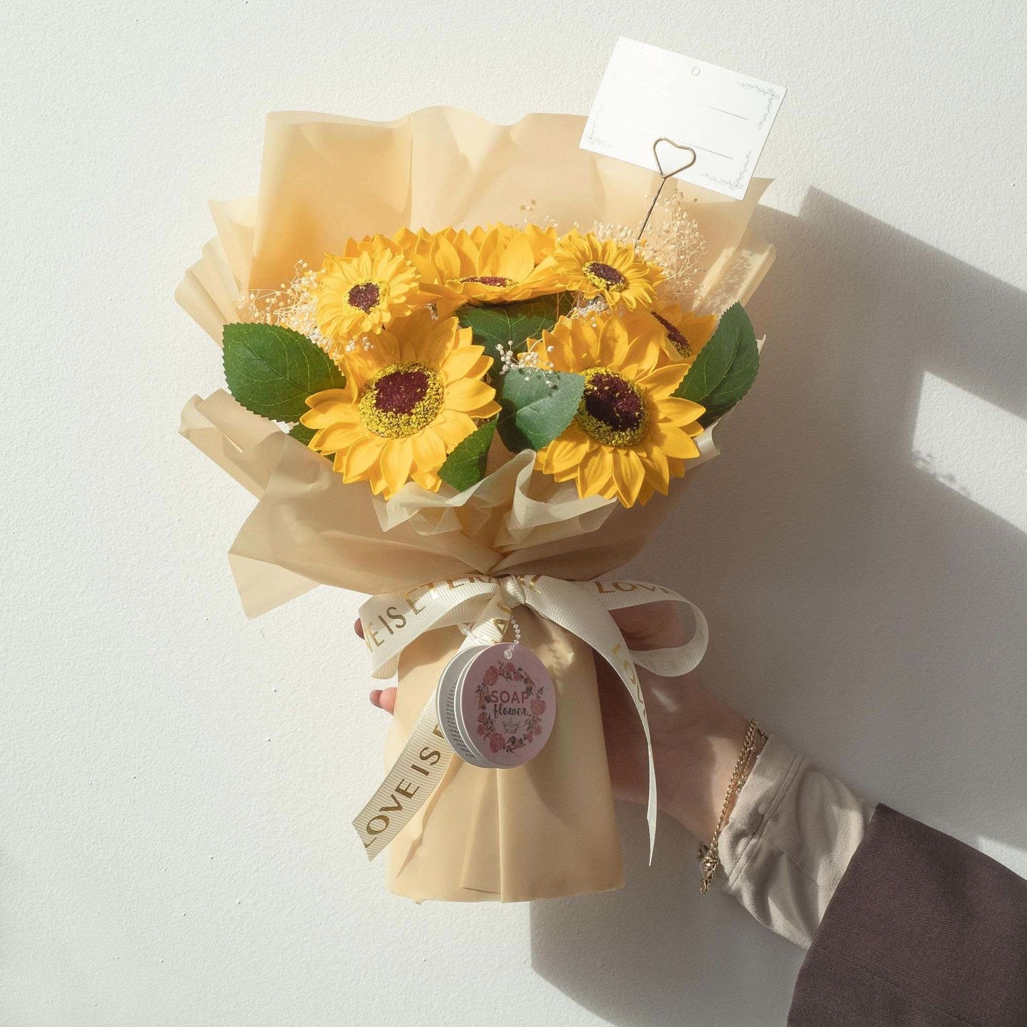 Large sunflowers bouquet with soap petals wrapped in golden paper and ribbon saying Love is Eternal with matching gift card