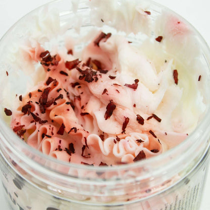 Close-up of creamy pink and white coconut whipped soap with delicate shavings in jar