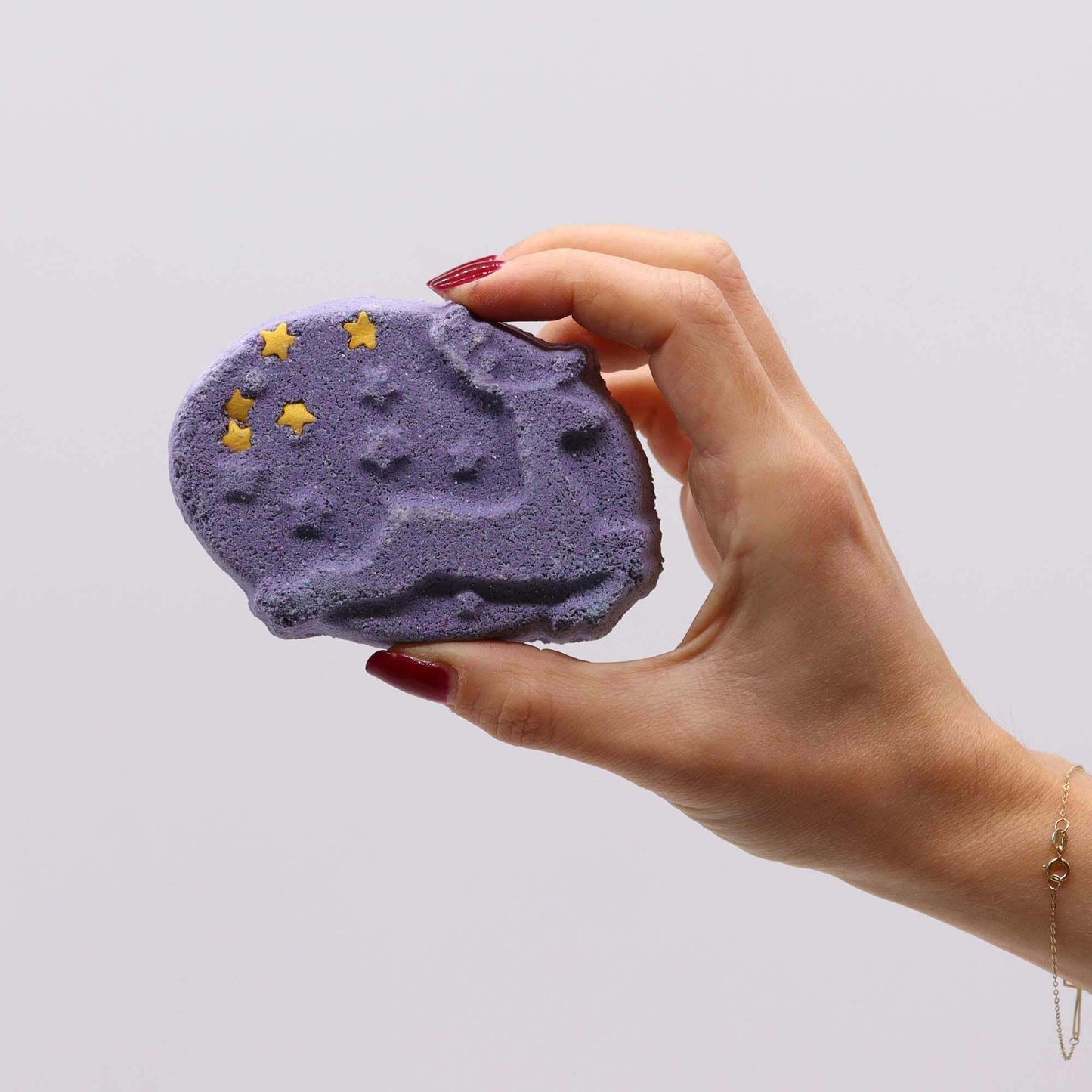Hand holding purple Christmas Fun Bath Bomb with star decorations