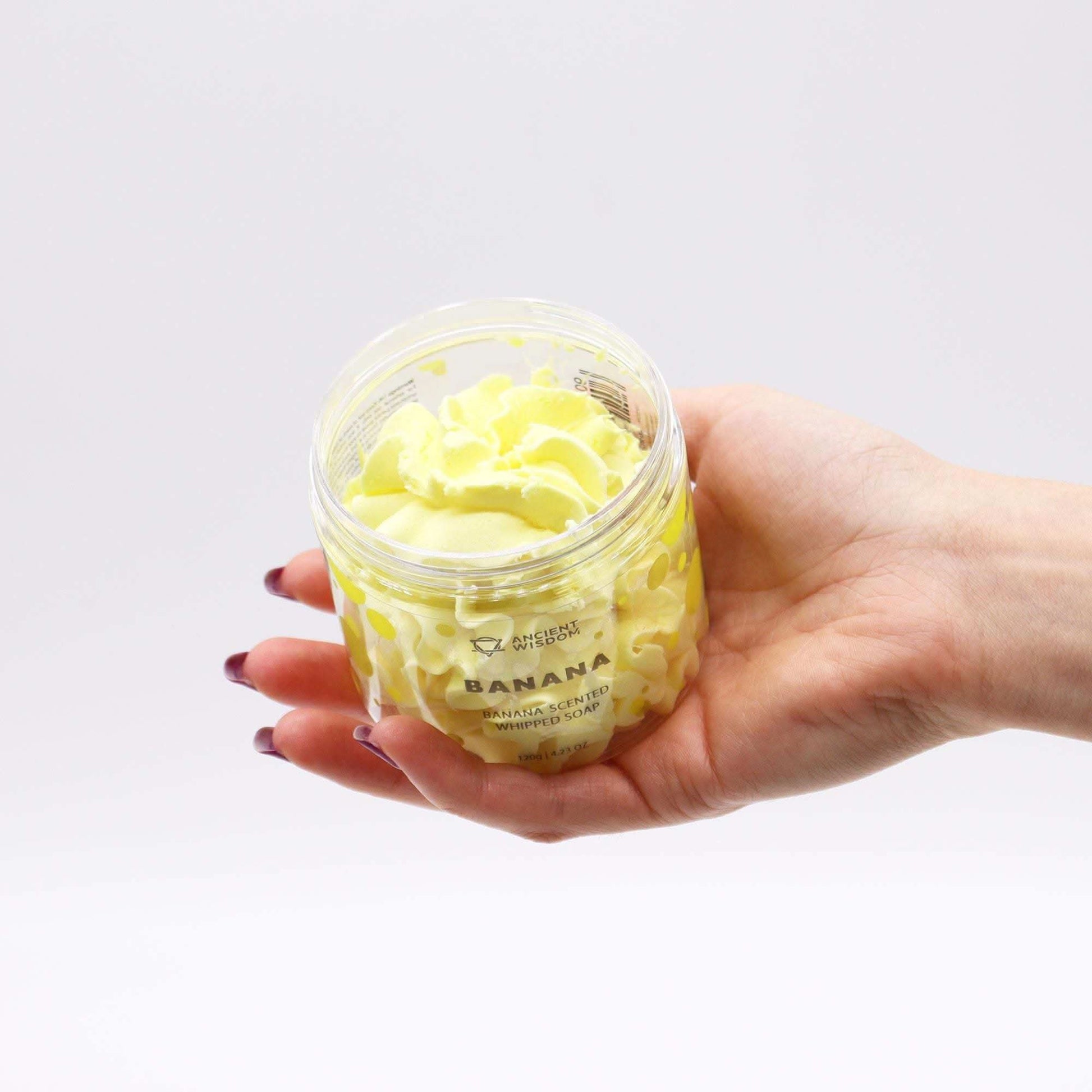 Hand holding yellow banana scented fruity whipped soap in clear tub from Fruity Whipped Soap Bundle by Ancient Wisdom