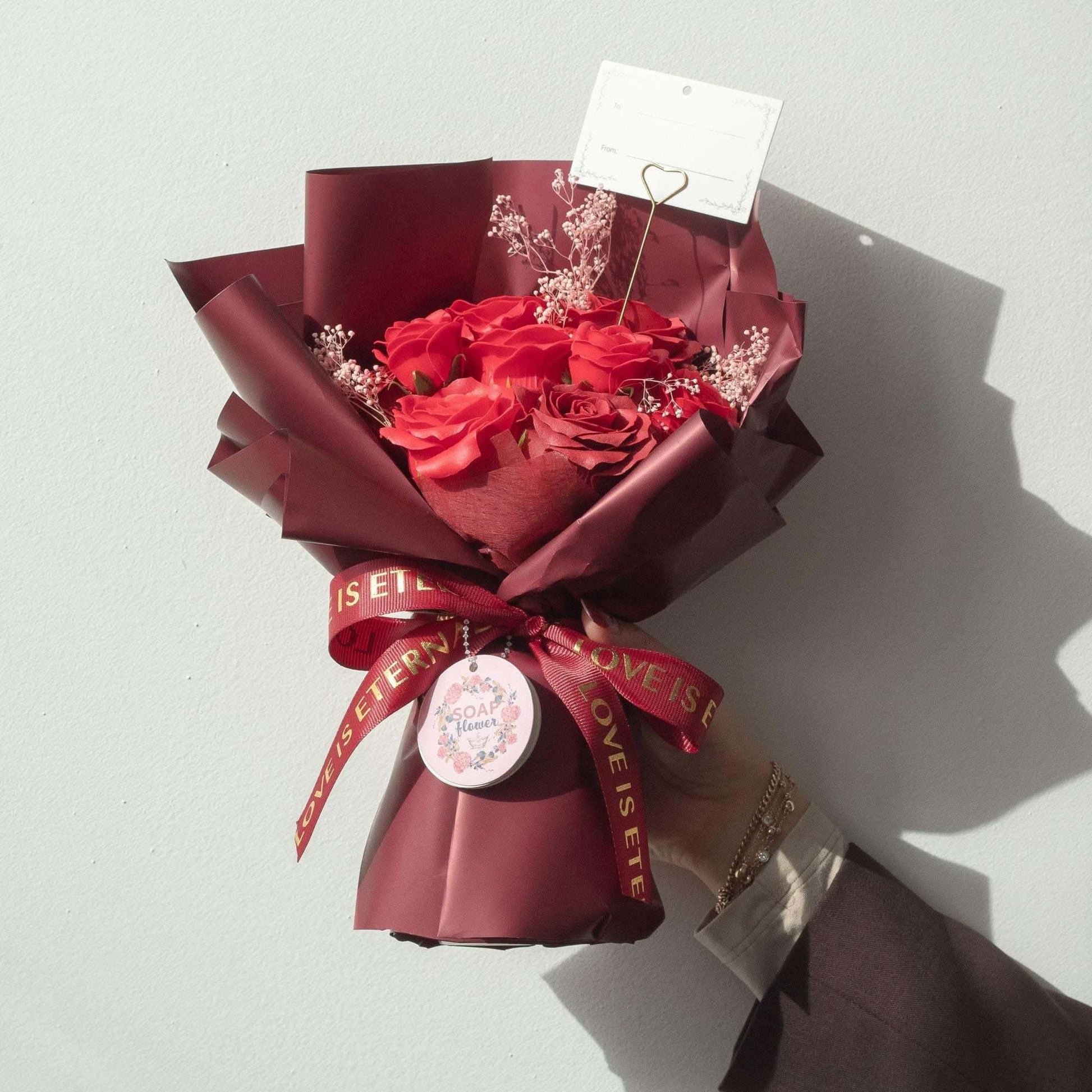 Large red roses bouquet of soap flowers wrapped in wine paper with satin ribbon and gift card
