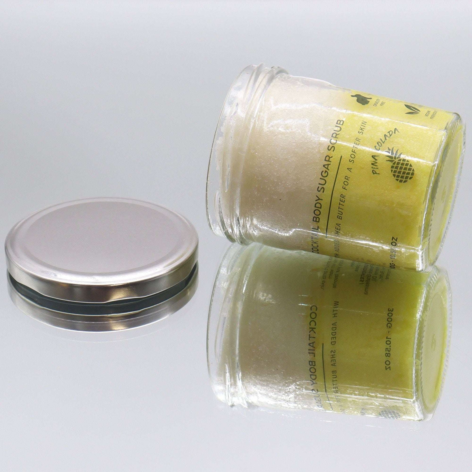 Fragranced sugar body scrub in clear jar with silver lid, pinacolada scent, 300g container