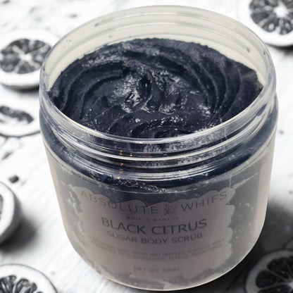Black Citrus Sugar Body Scrub in a clear jar showing deep black, smooth textured scrub with citrus slices in the background
