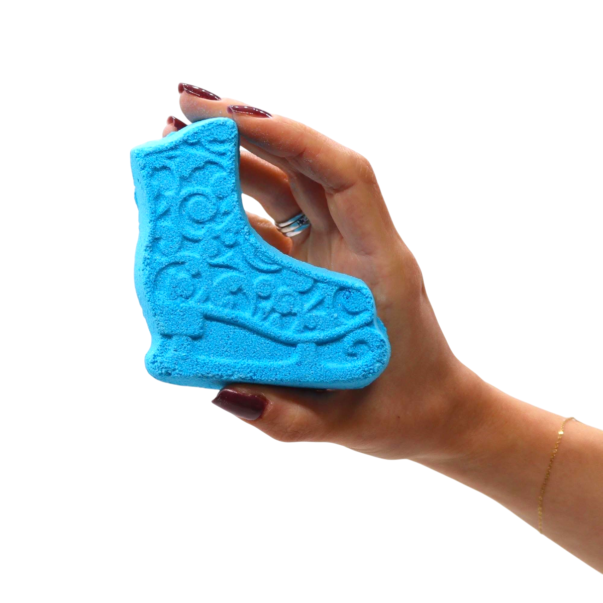 Blue ice skate shaped bath bomb with embossed detailing, held in a hand showcasing the Break the Ice Christmas Bath Bomb Gift Pack