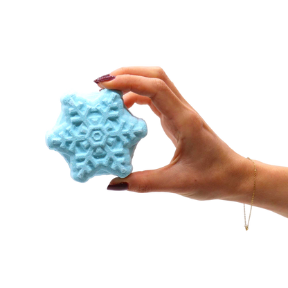 Hand holding a light blue star-shaped bath bomb with an intricate snowflake pattern, part of the Break the Ice Christmas Bath Bomb Gift Pack