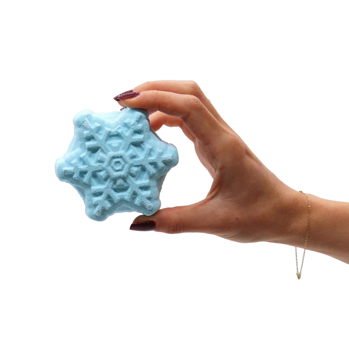 Christmas Bath Bomb Gift Pack featuring a hand holding a blue snowflake-shaped bath bomb with intricate textured patterns