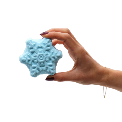 Christmas Bath Bomb Gift Pack featuring a hand holding a blue snowflake-shaped bath bomb with intricate textured patterns