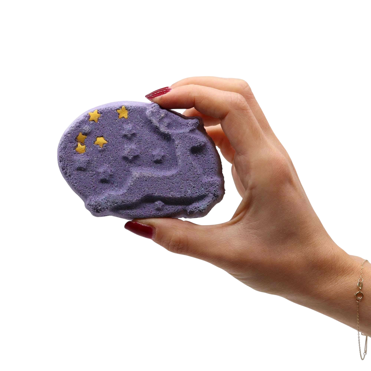 Christmas Fun Bath Bomb Gift Pack purple bath bomb with star-shaped yellow decorations held by hand with red nail polish
