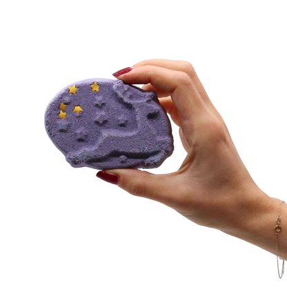 Christmas Fun Bath Bomb Gift Pack purple bath bomb with star-shaped yellow decorations held by hand with red nail polish
