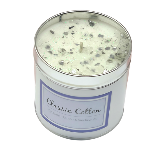 Classic Cotton Seriously Scented Candle in a white container with glittery top and label reading Classic Cotton with scents of cyclamen, lemon, and sandalwood