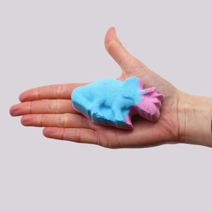 Dinosaur Bath bomb in blue and pink colors held in a hand, showing detailed dinosaur shape and smooth texture