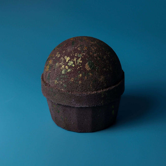 Dubai Bath Bomb shaped like a dark chocolate cupcake, with a rounded top and scattered green and gold flecks