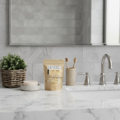 Absolute Whifs Energise Himalayan bath salt pouch with lemon, ginger, orange oils, and marigold flowers on a counter.