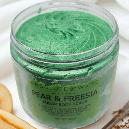 Pear & Freesia Sugar Body Scrub in a clear jar with green scrub and slices of pear nearby