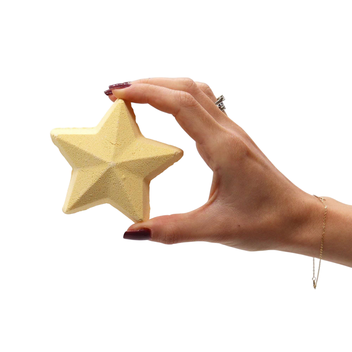 Hand holding a yellow star-shaped bath bomb with a smooth textured surface from the Follow the Star Christmas Bath Bomb Gift Pack