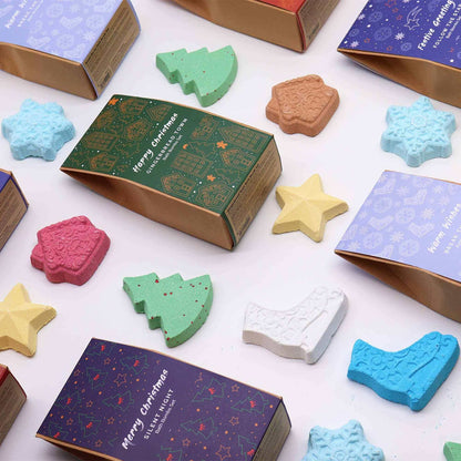 Gingerbread Town Christmas Bath Bomb Gift Pack featuring colorful festive-shaped bath bombs like stars, Christmas trees, snowflakes, and boots in pastel hues with decorative gift boxes