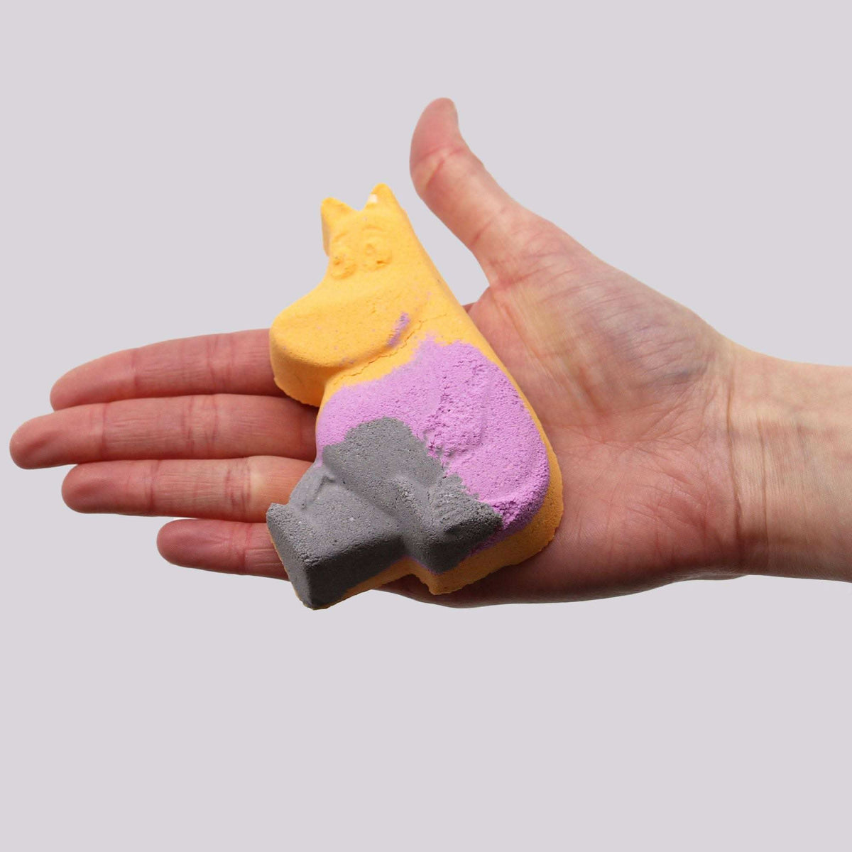 Hippo Bath bomb in orange, purple, and gray colors with a playful hippo shape held in a hand, showing its compact size and detail
