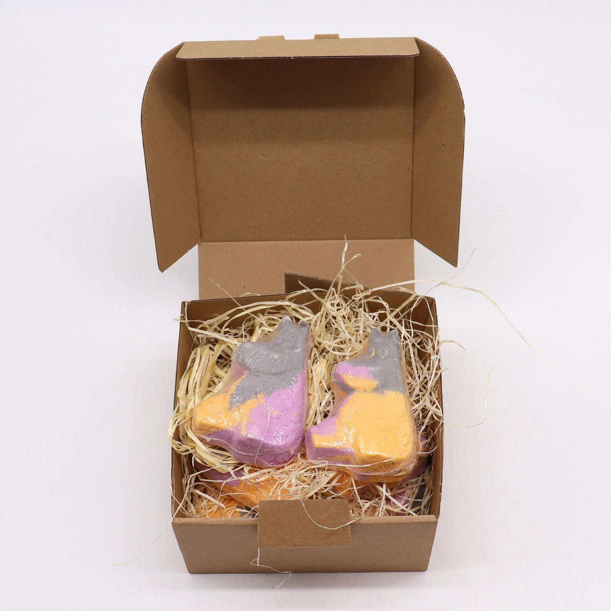 Hippo Bath bomb in purple and orange with a playful hippo shape, nestled in straw-like packing inside a brown cardboard box