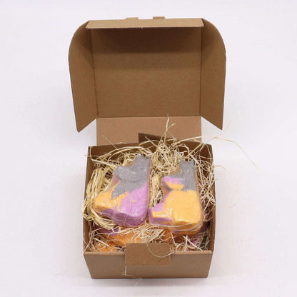 Hippo Bath bomb in purple and orange with a playful hippo shape, nestled in straw-like packing inside a brown cardboard box