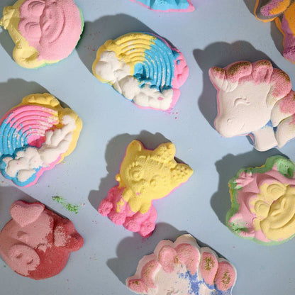 Hippo Bath bomb shaped like a yellow hippopotamus with pink details among various colorful rainbow and animal-shaped bath bombs on a light surface