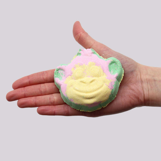 Monkey Bath bomb shaped like a smiling monkey head in pastel yellow, pink, and green colors made of foaming bath material