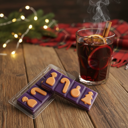 Mulled Wine Wax Melt Snap Bar in purple with orange festive shapes beside a steaming glass of mulled wine with cinnamon and orange slices