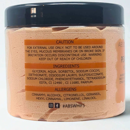 Peach and Papaya Sugar Body Scrub in a clear jar with black lid showing brownish peach-colored whipped texture and label with ingredients and caution details