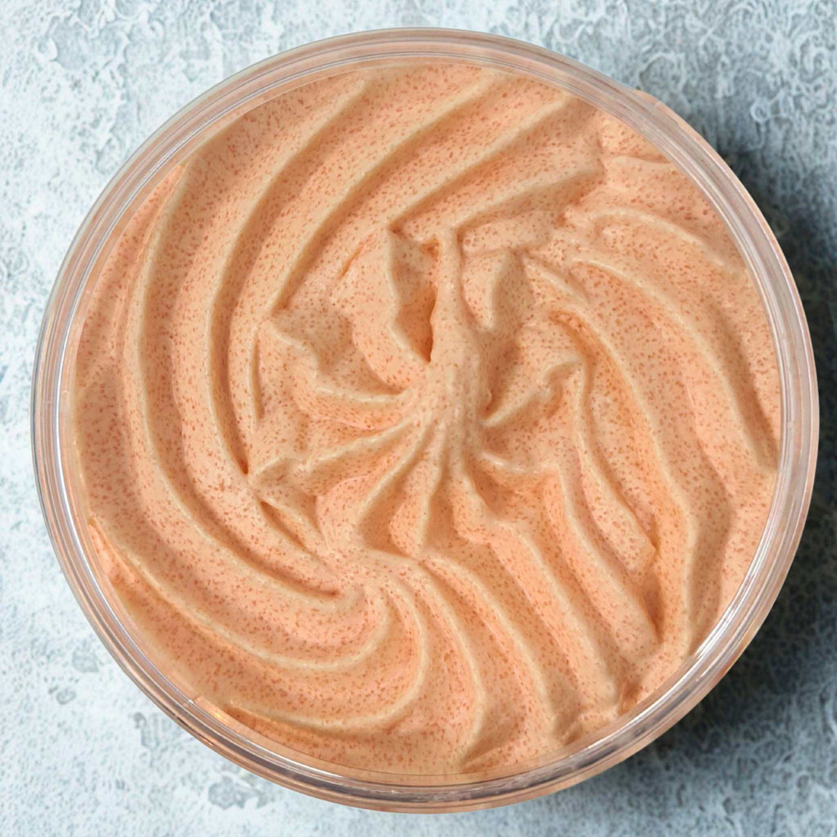 Peach and Papaya Sugar Body Scrub with whipped buttery texture in a clear round container showing creamy orange color with fine sugar granules