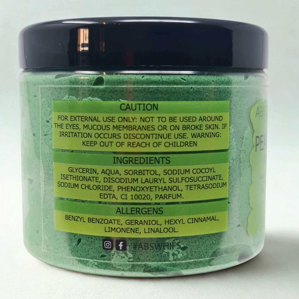 Jar of Pear and Freesia Sugar Body Scrub with green label displaying caution, ingredients, and allergen information on light green scrub base