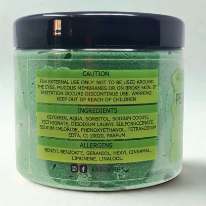 Jar of Pear and Freesia Sugar Body Scrub with green label displaying caution, ingredients, and allergen information on light green scrub base