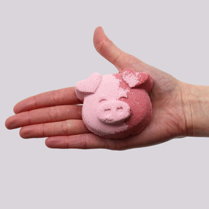 Pig Bath bomb shaped like a pig's face in two shades of pink with textured surface held in a hand