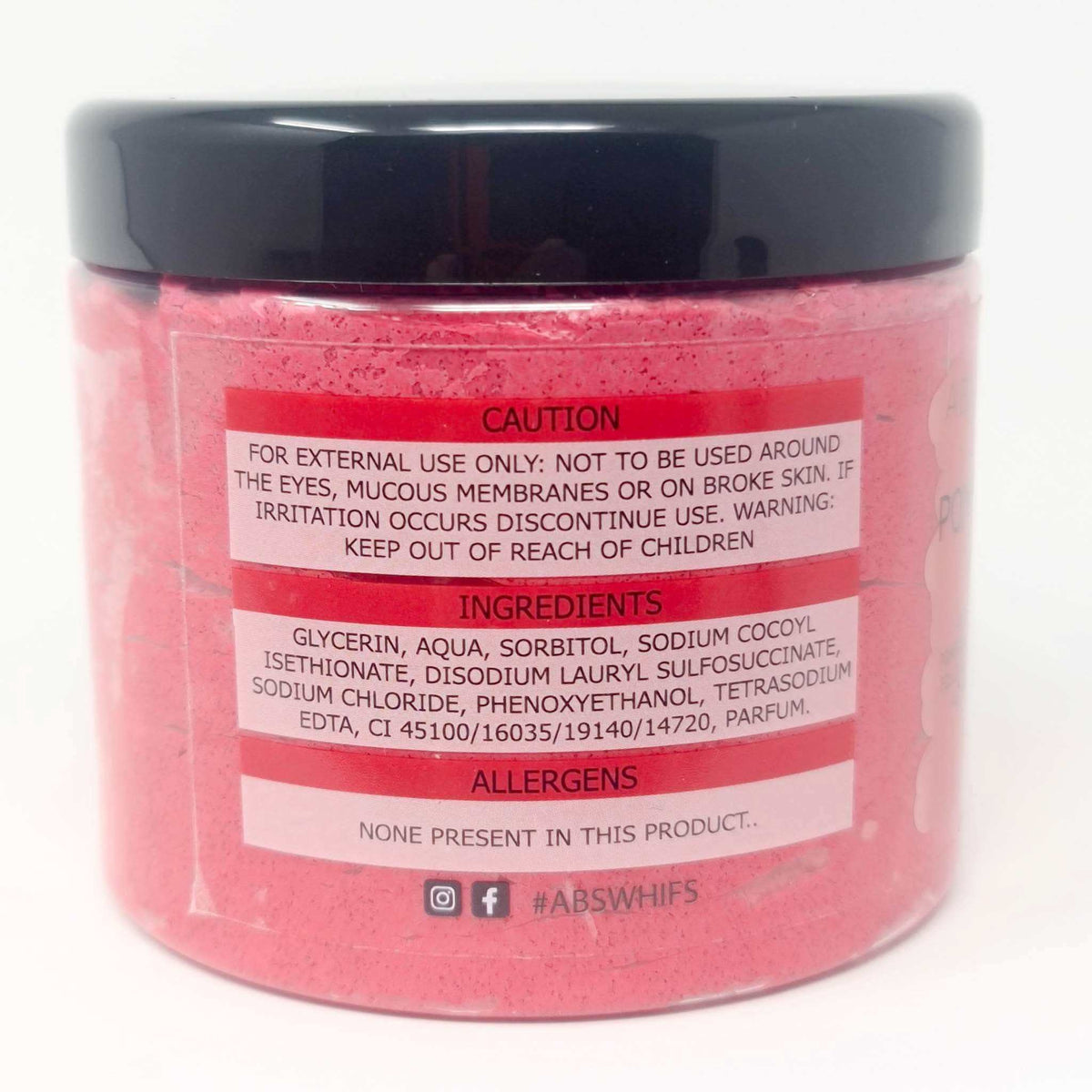 Pomegranate Noir Sugar Body Scrub in a clear round jar showing pink granular scrub with caution, ingredients, and allergens label
