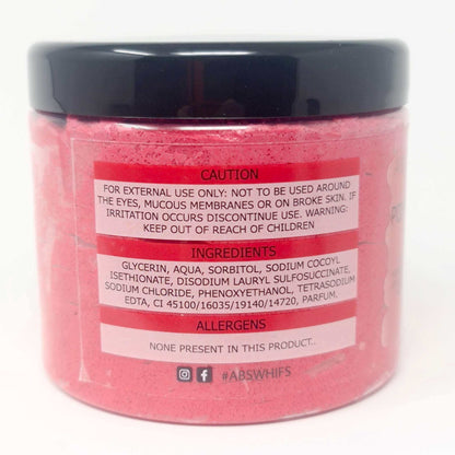 Pomegranate Noir Sugar Body Scrub in a clear round jar showing pink granular scrub with caution, ingredients, and allergens label