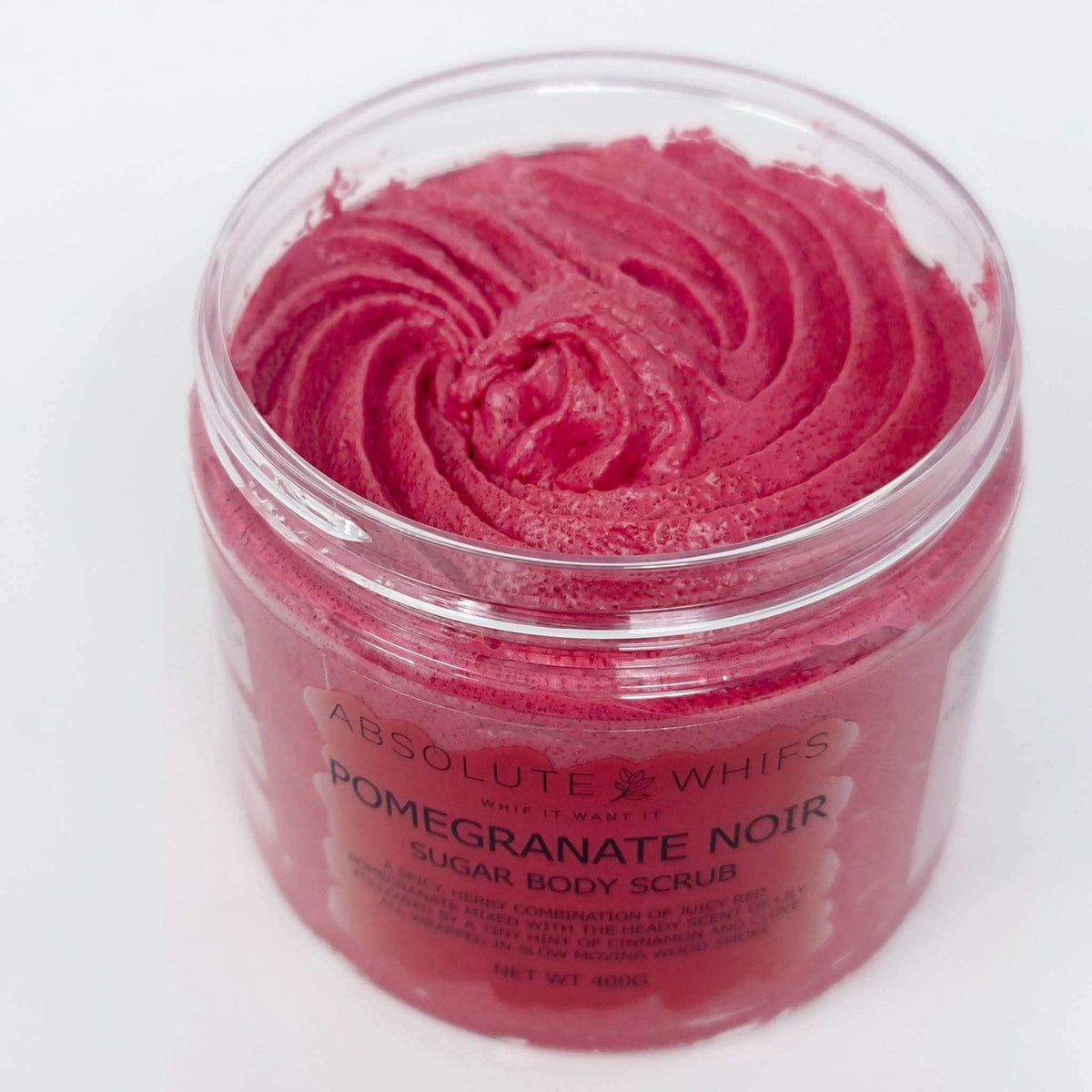 Pomegranate Noir Sugar Body Scrub in a clear jar showing rich deep red textured cream with swirled top surface