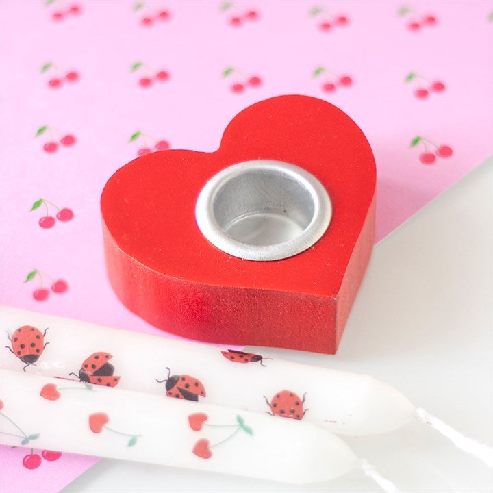 Red heart-shaped candle holder for taper candles on a decorative background.