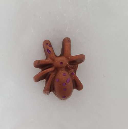 Halloween themed witches truffles wax melt shaped like a spider with brown and purple glitter.